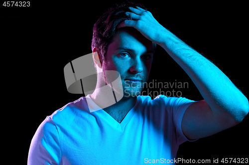 Image of man touching his hair over neon lights in darkness