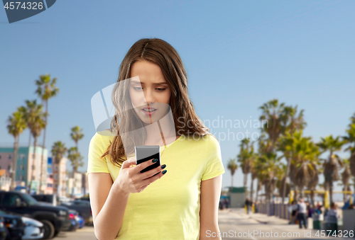 Image of teenage girl using smartphone over venice beach