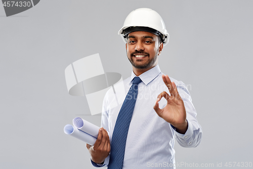 Image of architect in helmet with blueprints showing ok