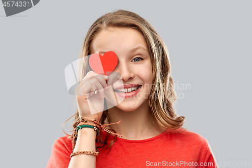 Image of smiling teenage girl covering eye with red heart