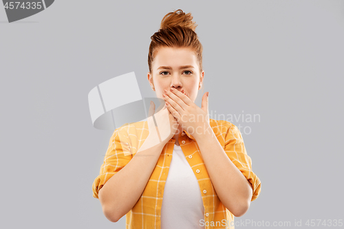 Image of red haired teenage girl covering mouth by hands