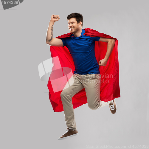 Image of man in red superhero cape jumping in air