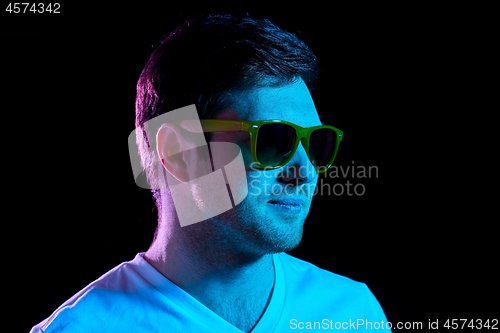 Image of man in sunglasses over ultra violet neon lights