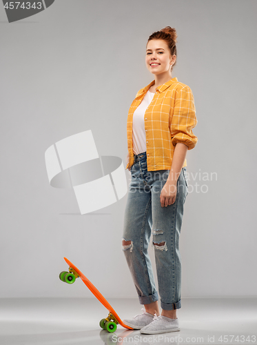 Image of red haired teenage girl with short skateboard