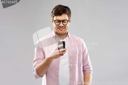 Image of young man in glasses looking at smartphone