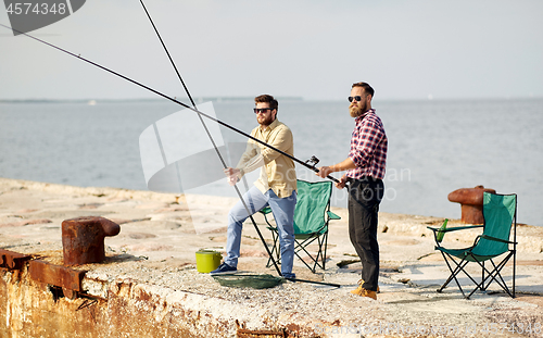 Image of happy friends with fishing rods on pier