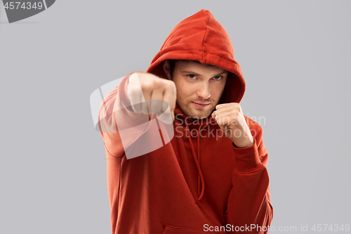 Image of man in red hoodie fighting with fists or boxing