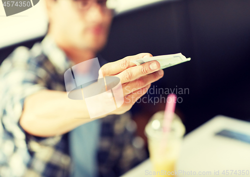 Image of happy man with cash money paying at cafe