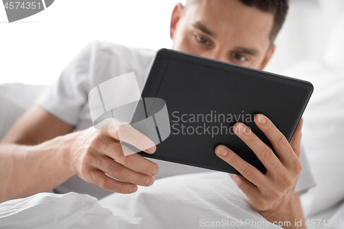 Image of close up of man with tablet computer in bed