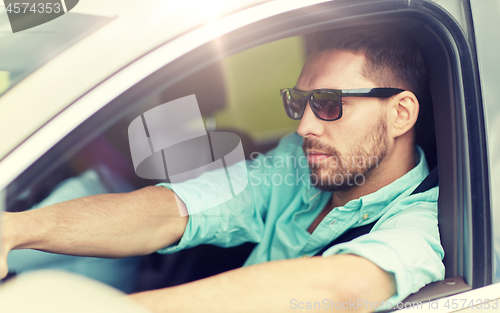 Image of young man in sunglasses driving car