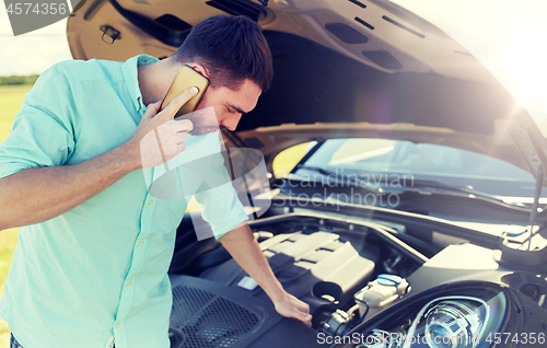 Image of man with broken car calling on smartphone