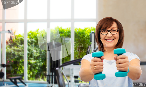 Image of smiling senior woman with dumbbells exercising