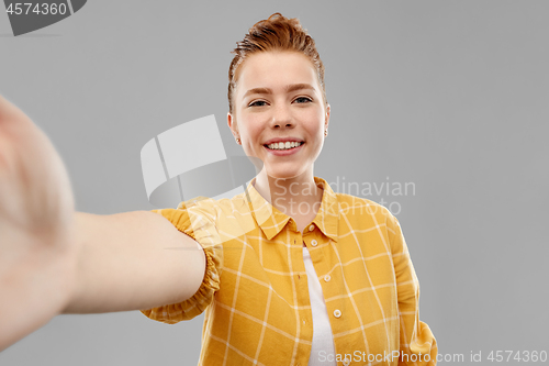 Image of smiling red haired teenage girl taking selfie