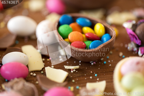 Image of chocolate egg and candy drops on wooden table