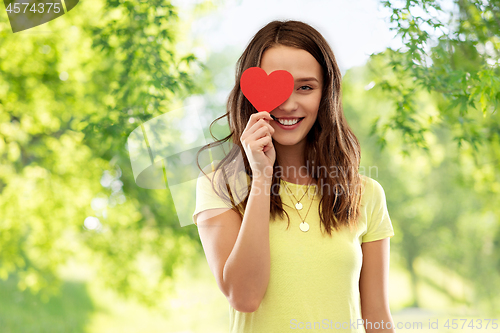 Image of smiling teenage girl covering her eye by red heart