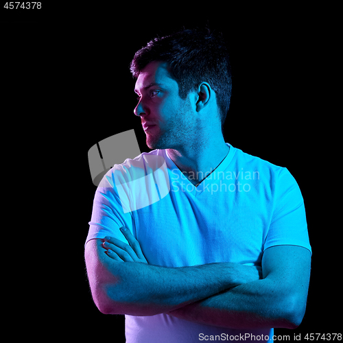 Image of man with crossed arms over neon lights in darkness