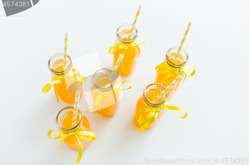 Image of orange juice in glass bottles with paper straws