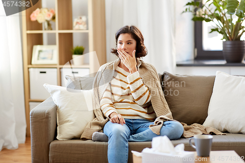 Image of sick woman in blanket coughing at home