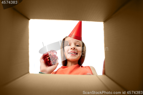 Image of birthday girl in party hat looking into gift box