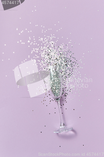 Image of The glass of champagne with bright silver confetti with soft shadows.
