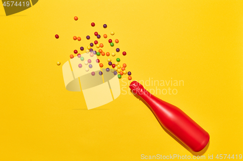 Image of Red painted champagne bottle with colorful candies.
