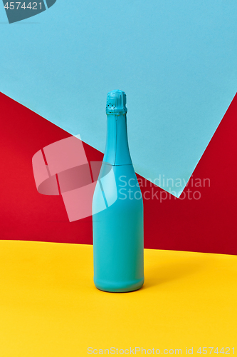 Image of Decorative painted blue champagne bottle on a tricolor background.