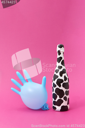 Image of Balloon rubber glove with painted white bottle with black spots.