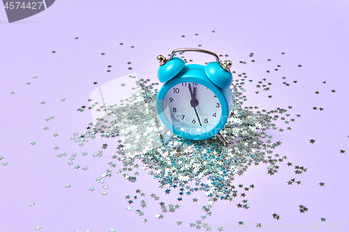 Image of Blue vintage alarm clock on a lavender background with silver glitter.