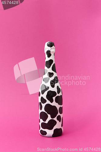 Image of White painted wine bottle with black spots.