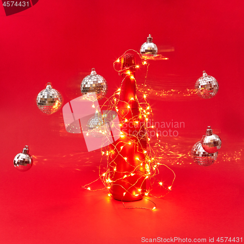 Image of Flying Cristmas balls around painted wine bottle with string of lights.
