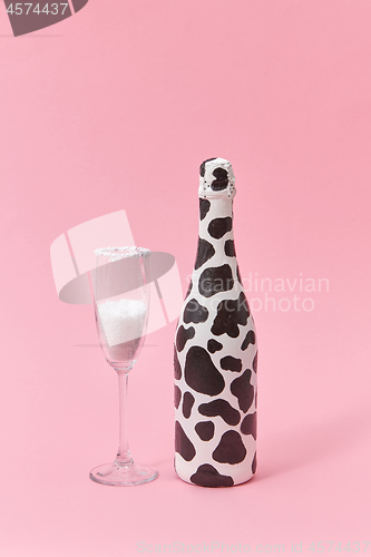 Image of Creative painted wine bottle with black spots and glass of white powder.