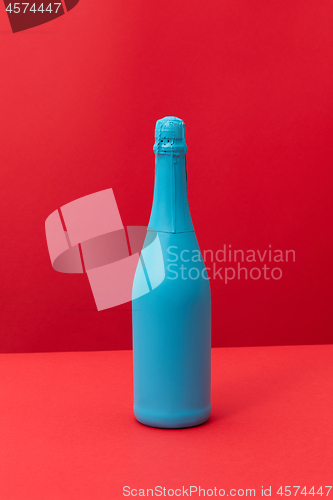 Image of Blue painted spray wine bottle on a duotone red background.