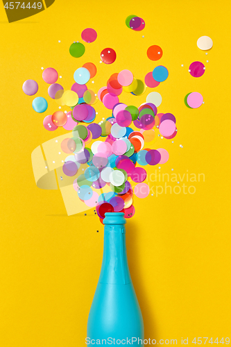 Image of Multicolored confetti as a bubble foam above open champagne bottle.