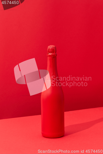 Image of Red painted spray wine bottle on a duotone red background.