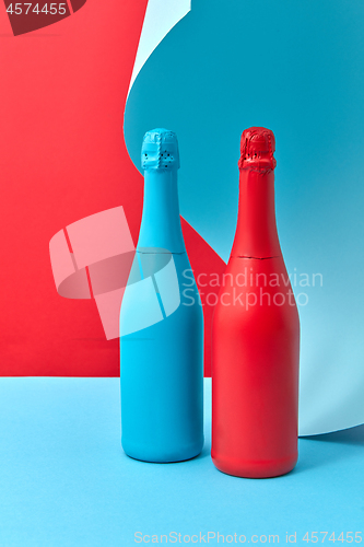 Image of Wine bottles mock-up painted red and blue on a duotone curly background.