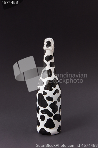 Image of Holiday painted wine bottle with black spots on a dark gray.