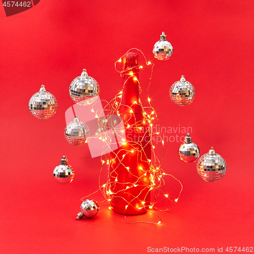 Image of Wine bottle painted red covered garland with lights and flying balls.