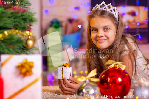 Image of Girl holding a small pretty gift in her hands, and looks into the frame