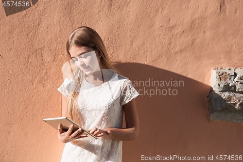 Image of beautiful young woman in white dress using tablet