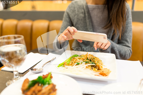 Image of Woman taking photo on dishes in restaurant