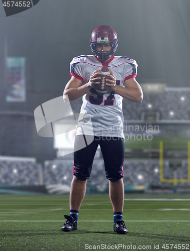 Image of portrait of confident American football player standing on the f