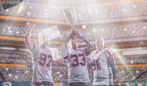 Image of american football team with trophy celebrating victory in the cu