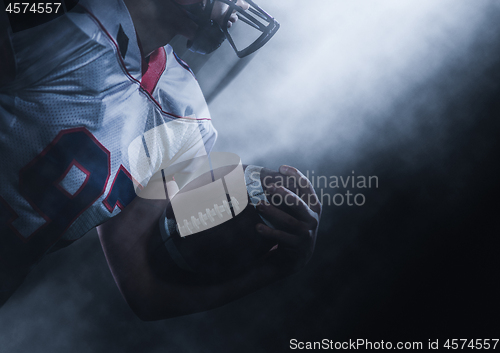 Image of American football player holding ball while running on field