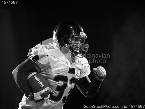 Image of American football player holding ball while running on field