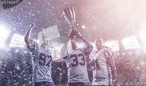 Image of american football team with trophy celebrating victory in the cu