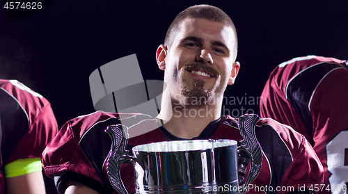 Image of american football team with trophy celebrating victory