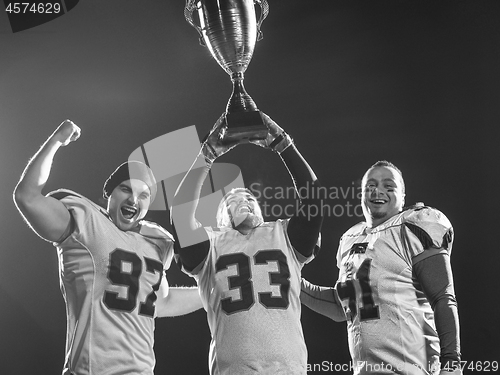 Image of american football team with trophy celebrating victory