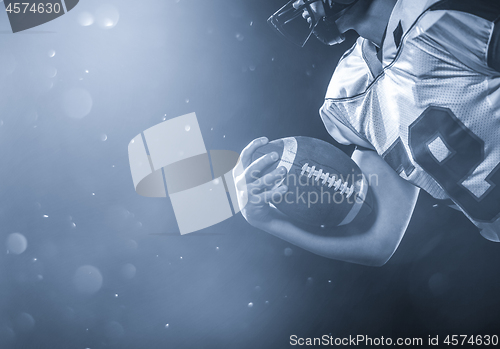 Image of American football player holding ball while running on field