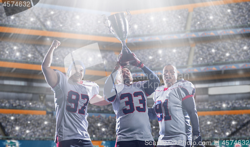 Image of american football team with trophy celebrating victory in the cu