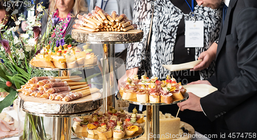 Image of Businesspeople at banquet lunch break at business conference meeting. Assortment of canapes and finger food on the table.